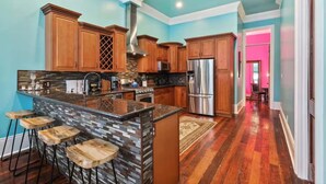 A modern kitchen with wooden cabinets, a stainless steel refrigerator, and a bar area with stools.