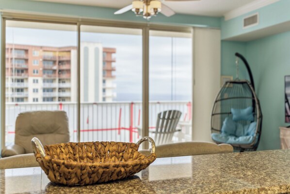 A kitchen with a woven basket on the counter, a chair, and a hanging chair with a cushion.