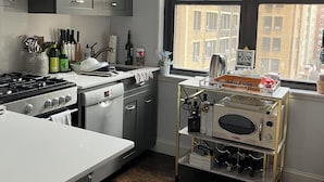 Una cocina moderna con armarios oscuros, horno empotrado, microondas y una vinoteca.