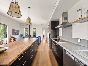 A modern kitchen with a wooden island, black cabinetry, and stainless steel appliances.