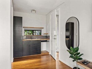 Une cuisine moderne avec des meubles de couleur sombre, un plan de travail en bois et une fenêtre.
