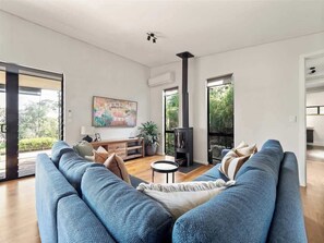 A modern living room with a sofa, a small table, a fireplace, and a painting on the wall.