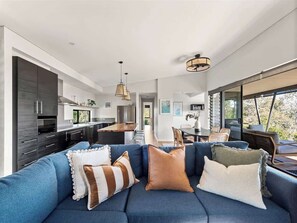 Una sala moderna con un sofá azul, una zona de cocina y un comedor.