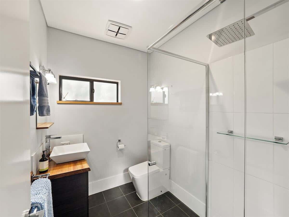 A modern bathroom with a glass shower enclosure, a white sink, and a toilet.
