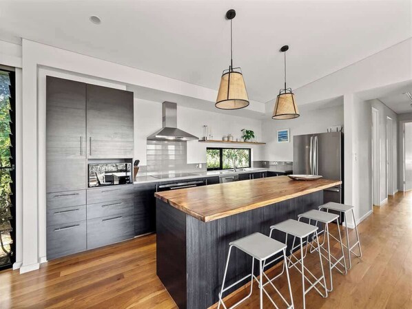 Una cocina moderna con una isla grande, taburetes de bar e iluminación colgante.