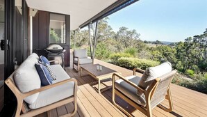 Una terrazza esterna coperta con posti a sedere, un barbecue e vista sul paesaggio circostante.