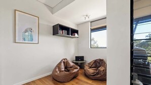 A modern room with a wooden floor, two bean bags, a bookshelf, a framed picture, and a window. - Wildflower Ridge: Elevated Forest & Coastal Escape (Western Australia)