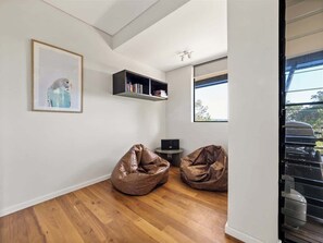 Una habitación moderna con suelo de madera, dos sillones de saco, una estantería, un cuadro enmarcado y una ventana.