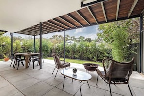 An outdoor patio with a table and chairs, a fire pit, and a view of the surrounding greenery.