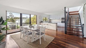 A modern kitchen with a central island, a dining area with a table and chairs, and a staircase leading to an upper level. - Arbre Retreat—Serene Bushland Escape Near Beach (Dunsborough)