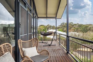 Un balcone con mobili in vimini, un'amaca e vista sul paesaggio circostante.