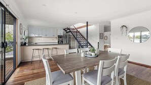 A modern kitchen with white cabinets, a wooden dining table, and a staircase leading to an upper level. - Arbre Retreat—Serene Bushland Escape Near Beach (Dunsborough)