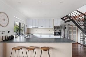 A modern kitchen with white cabinets, a granite countertop, and a built-in island with bar stools.