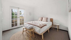 Una camera da letto con un letto, una panca, un tavolino e vista attraverso una porta scorrevole.