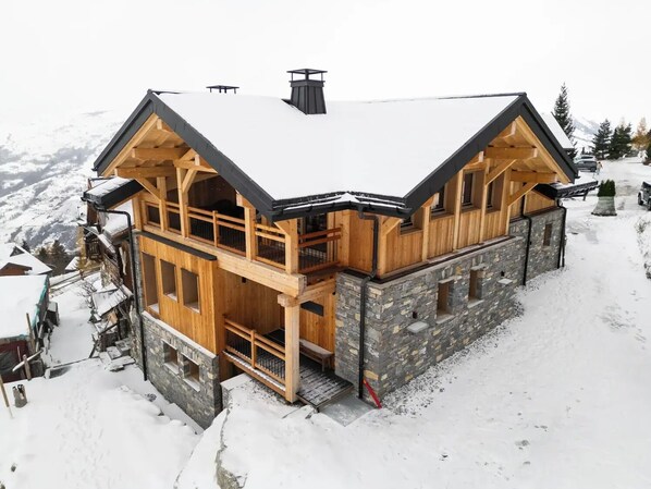 A multi-level wooden chalet with stone walls, balconies, and a snow-covered roof. - Chalet Le Rokh - Luxury ski in/out chalet in Peisey&Vallandry (Landry)