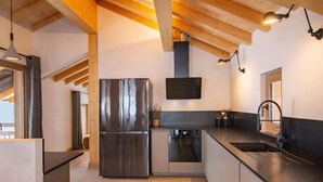 Cocina moderna con refrigerador de acero inoxidable, horno empotrado y encimeras negras.