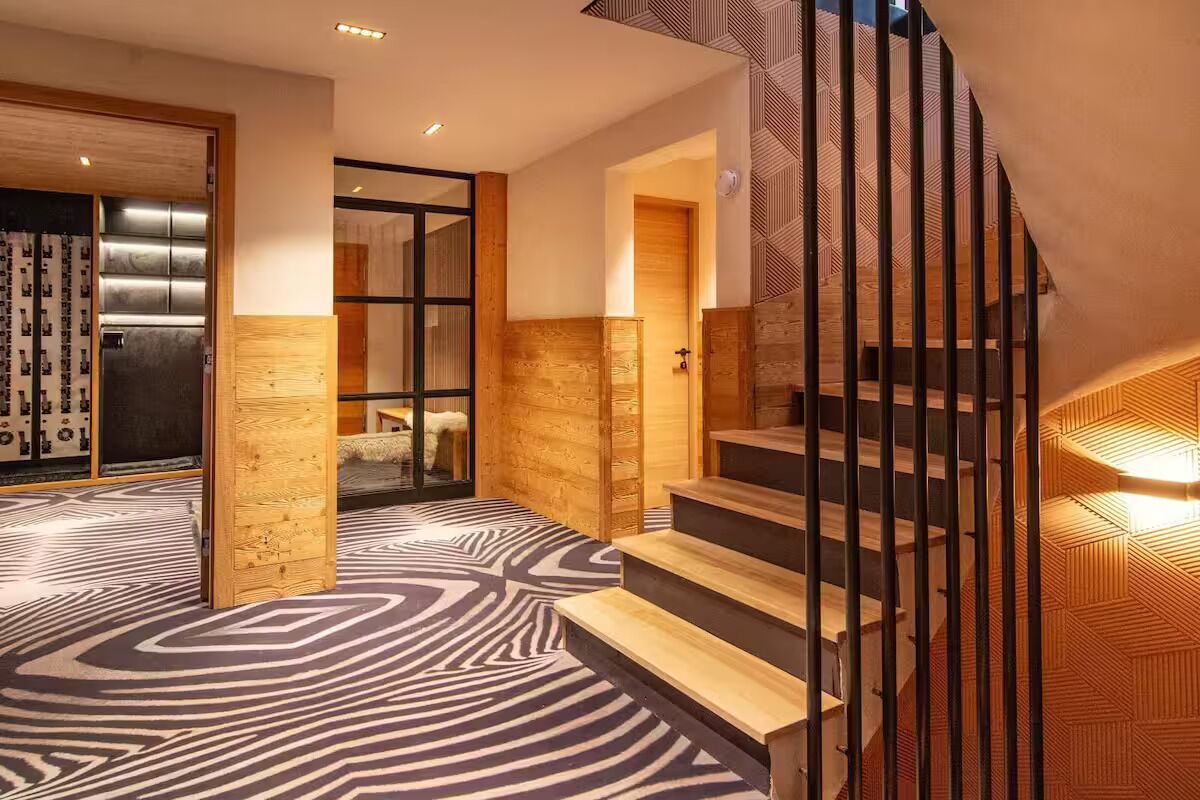 A modern interior with a patterned carpet, wooden walls, and a staircase with metal railings.