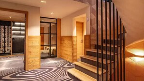 Un interior moderno con alfombra estampada, paredes de madera y una escalera con barandillas de metal.