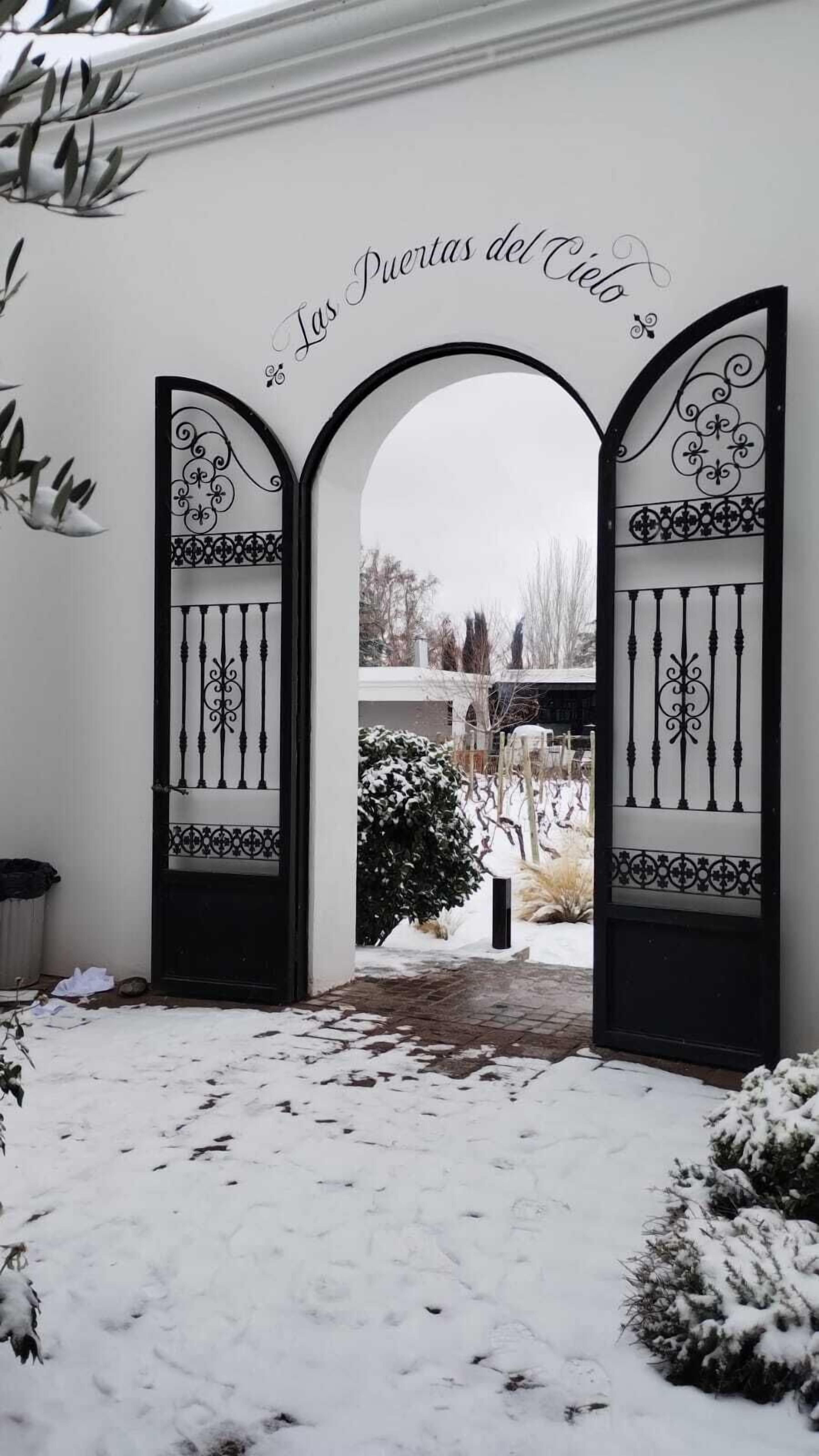 A snow-covered entrance with a decorative gate and a sign above it.