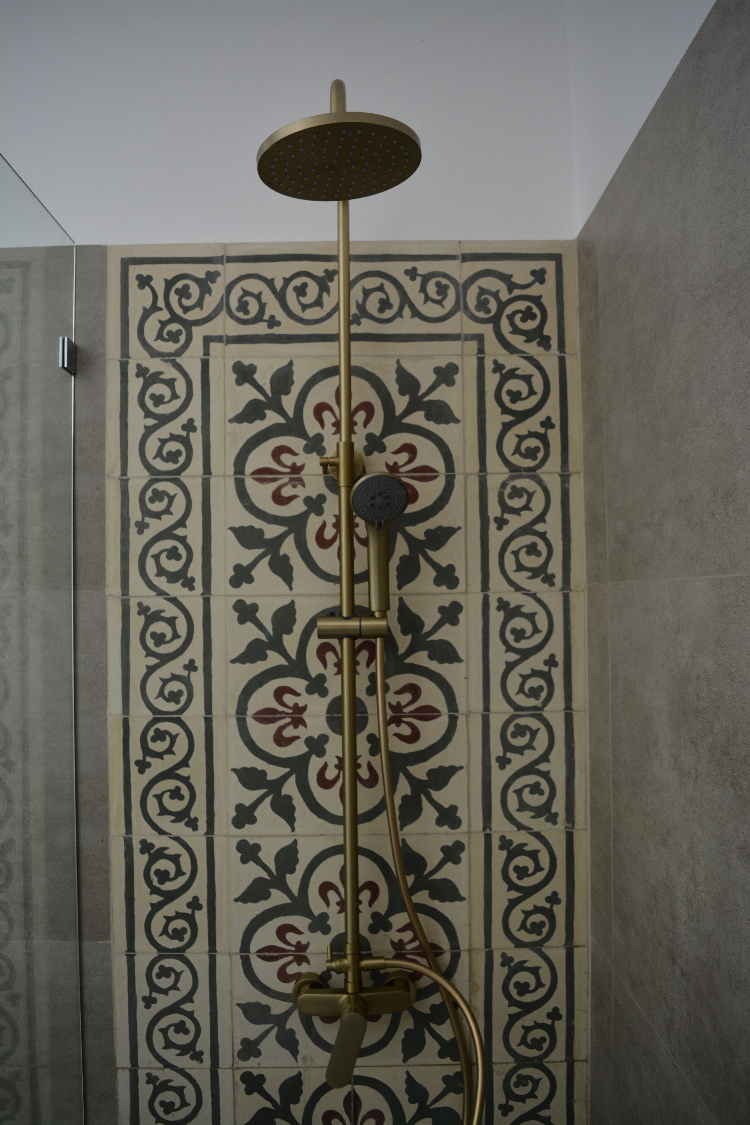 Una ducha con cabezal dorado y panel de control negro.