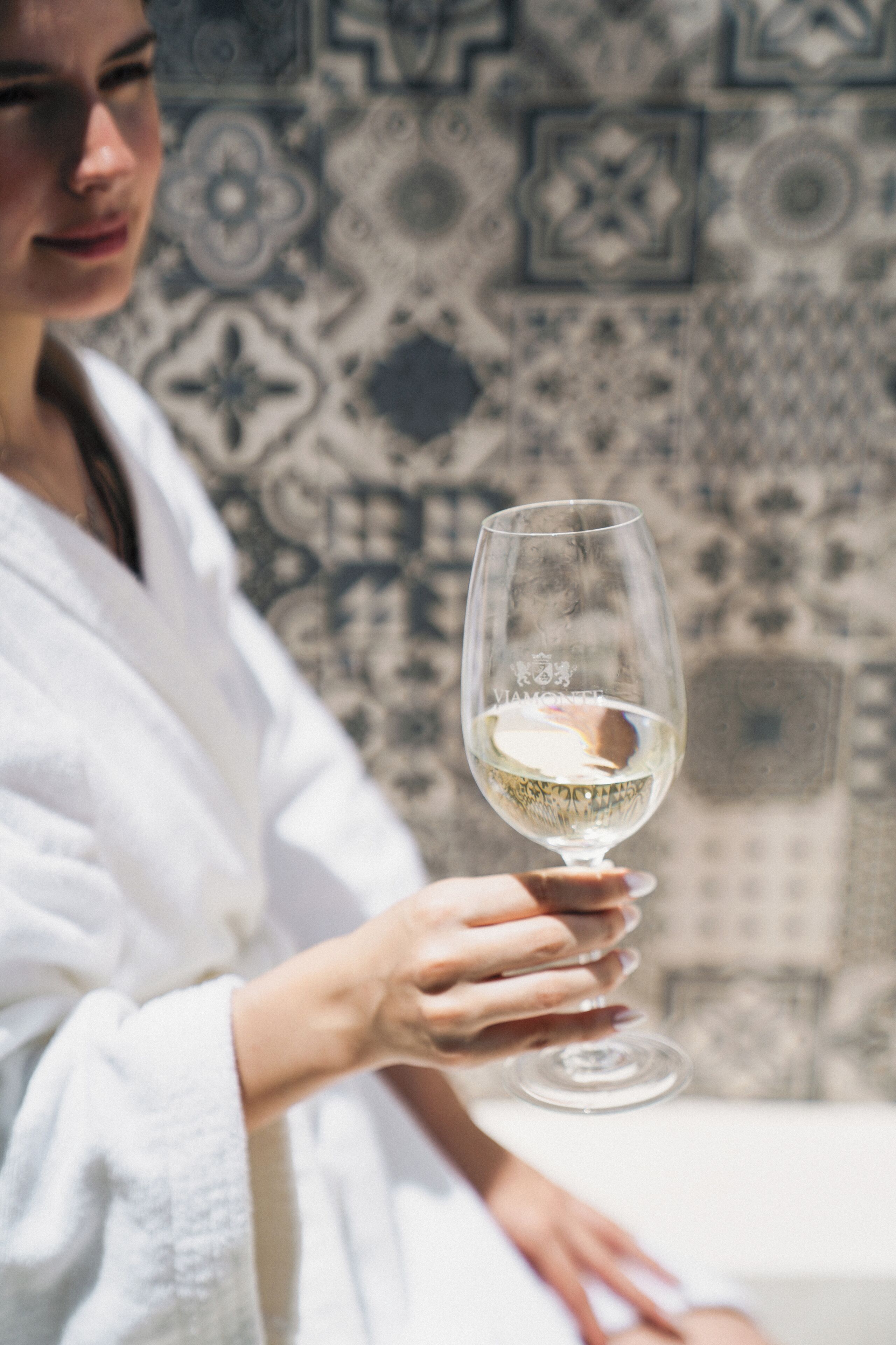 A person in a white robe holding a wine glass.