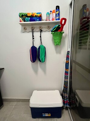 A storage area with a white shelf holding various items, a green basket, and a blue cooler on the floor. - 3-bedroom house with Solar Energy, Water cistern, AC, and high speed internet. (Canaboncito)