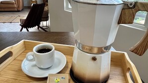 A wooden tray with a coffee pot, a cup of coffee, and a packet of Dulce Caná. - 3-bedroom house with Solar Energy, Water cistern, AC, and high speed internet. (Canaboncito)