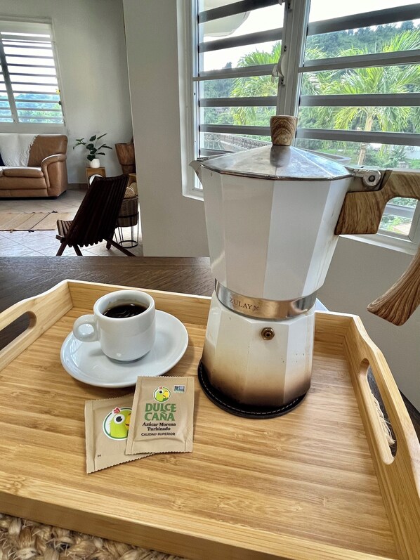 A wooden tray with a coffee pot, a cup of coffee, and a packet of Dulce Caná. - 3-bedroom house with Solar Energy, Water cistern, AC, and high speed internet. (Canaboncito)