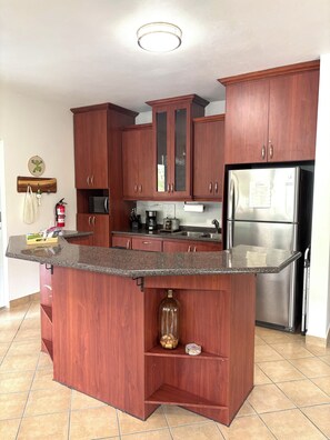 A kitchen with wooden cabinets, a stainless steel refrigerator, and a granite countertop.