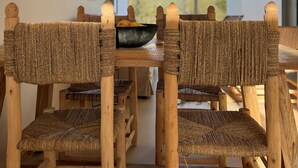 A dining area with woven chairs and a hanging light fixture. - CASA DO REGADIO - HOUSE 2, A country and sea retreat on the Alentejo coast,  (Zambujeira do Mar)