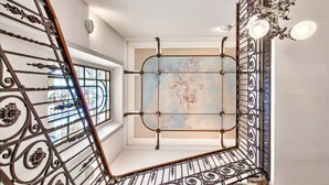 A staircase with ornate metal railings and a chandelier, leading to a room with a decorative ceiling and a window with stained glass. - Historic Villa in Como Center + 4 free parking (Como)