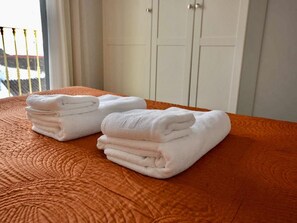 A bed with a textured orange bedspread and two neatly folded white towels. - Modern one bedroom apartment in the heart of Nerja (Nerja)