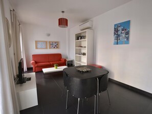 Una sala de estar moderna con un sofá rojo, una mesa de comedor negra y una estantería blanca.