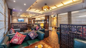 Un moderno vestíbulo de hotel con asientos de cuero, una zona de bar y una pantalla de televisión.