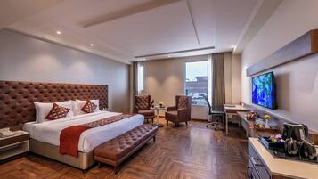 A modern hotel room with a large bed, a desk, a television, and a view of the city.