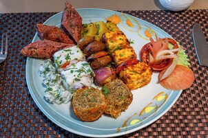 A plate of food with various items including grilled vegetables, a piece of meat, and a bread roll.