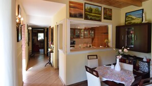 Una cucina con isola centrale, zona pranzo con tavolo e sedie, e salotto con divano e televisore.
