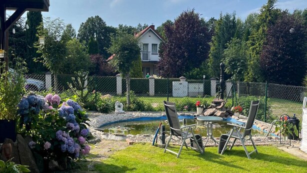 Un giardino con piscina, prato e una casa sullo sfondo.