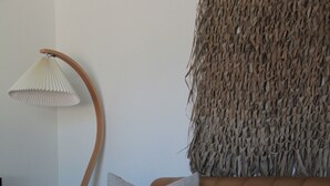 Ein modernes Wohnzimmer mit einem braunen Ledersofa, einem Holztisch und einer gewebten Wanddekoration.