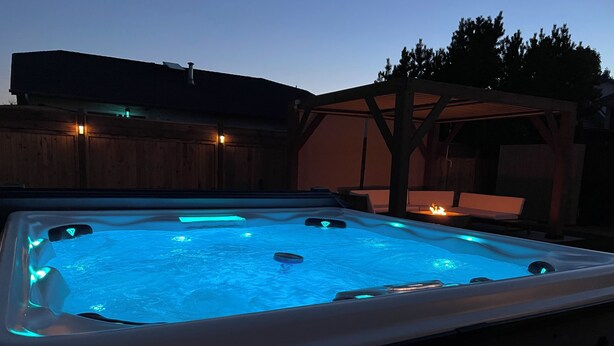 Ein Whirlpool mit einer Holzterrasse und einer Pergola im Hintergrund.
