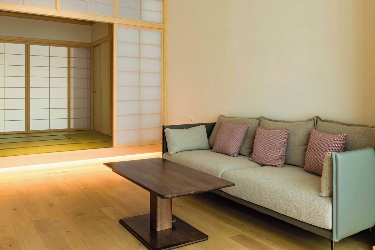 Uma sala de estar com sofá, almofadas, mesa de centro e uma porta deslizante com painéis de vidro jateado.