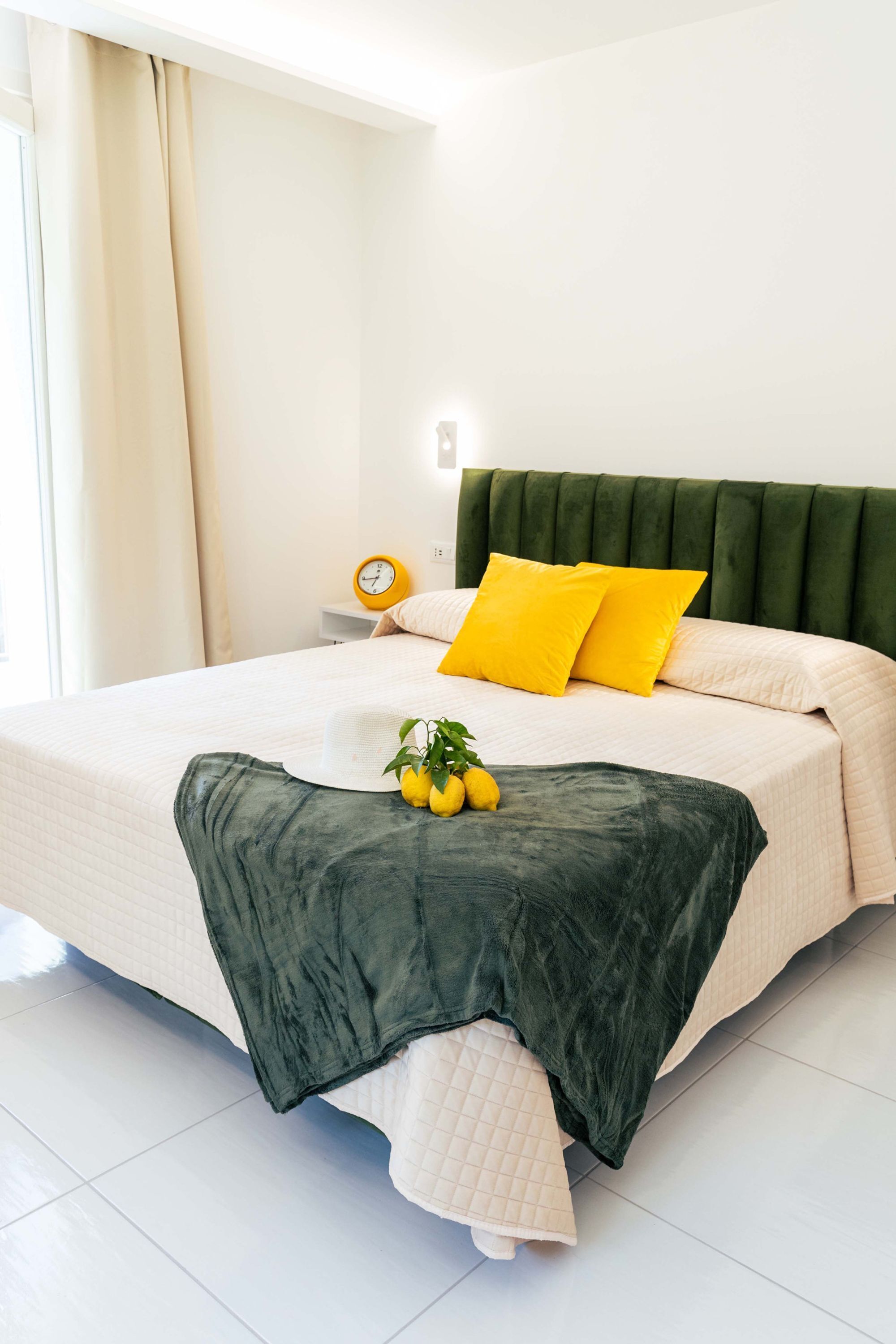 A neatly made bed with a green headboard, white bedding, and two yellow pillows.