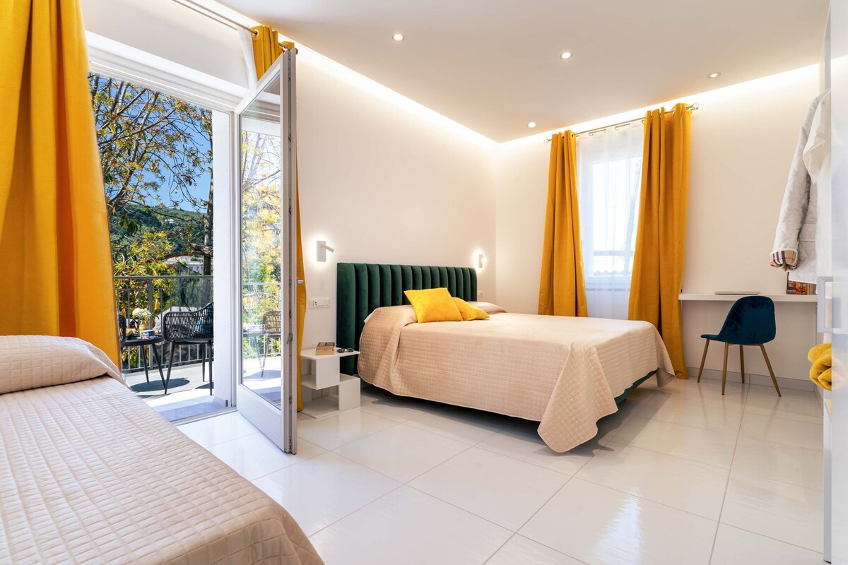 Une chambre moderne avec un lit, un bureau et une chaise. Une porte-fenêtre coulissante donne accès à un espace extérieur aménagé avec une table et des chaises.