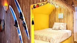 A room with a bed, a surfboard, and a surfboard rack. - The Retreat at Bethany Beach Cove (Sussex County)