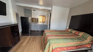 A compact room with a bed, a small kitchenette, and a wooden floor. - BORONDA INN (Salinas)