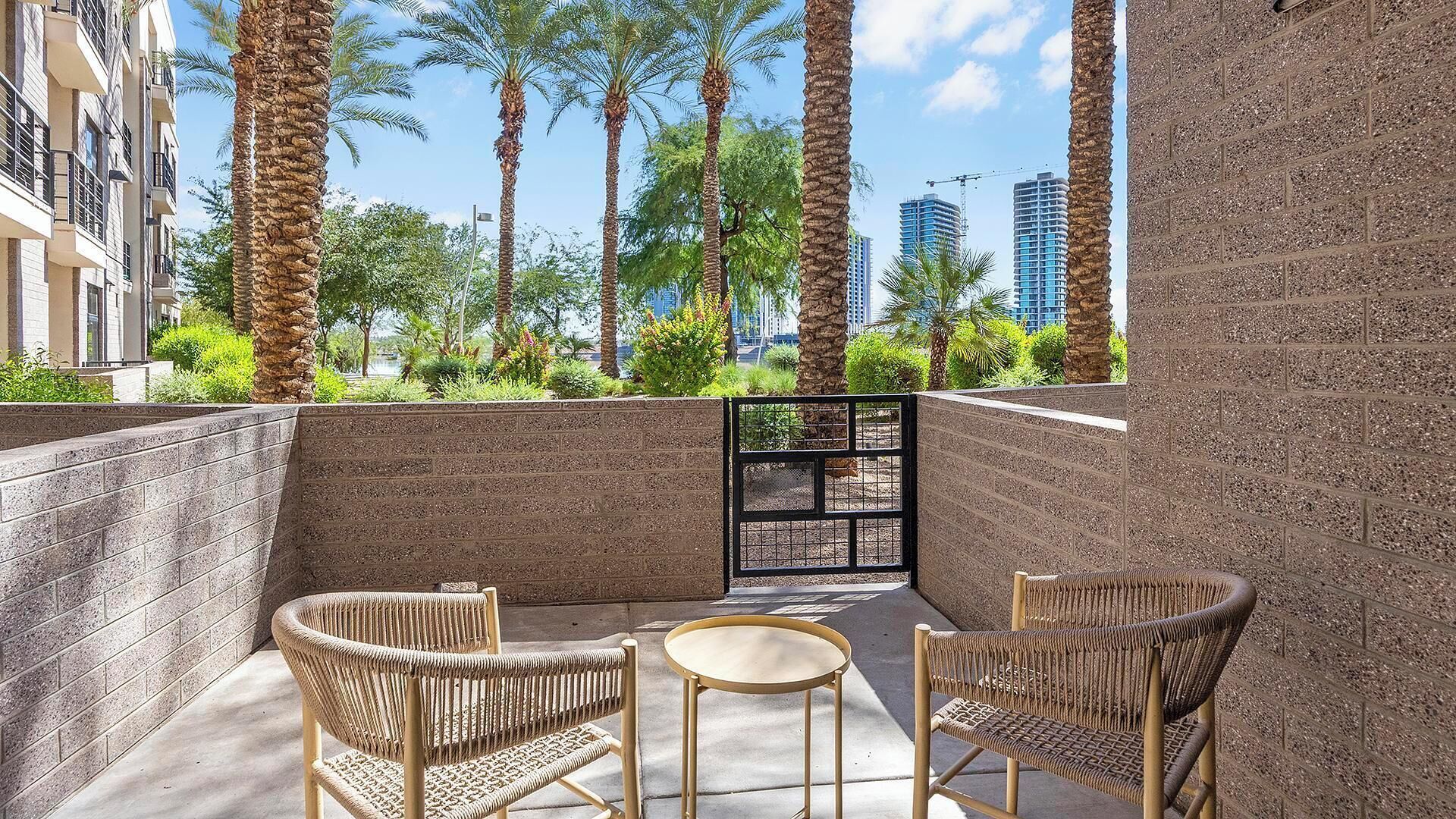 A balcony with wicker furniture, a small round table, and tall palm trees.