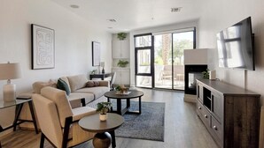 Ein modernes Wohnzimmer mit einer Couch, zwei Couchtischen, einem Fernseher und einem Kamin.
