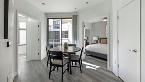 A hotel room with a bed, a round table with chairs, and a balcony with a view. - Landing | Modern 2BD, Clubhouse, Game Room (Tempe)