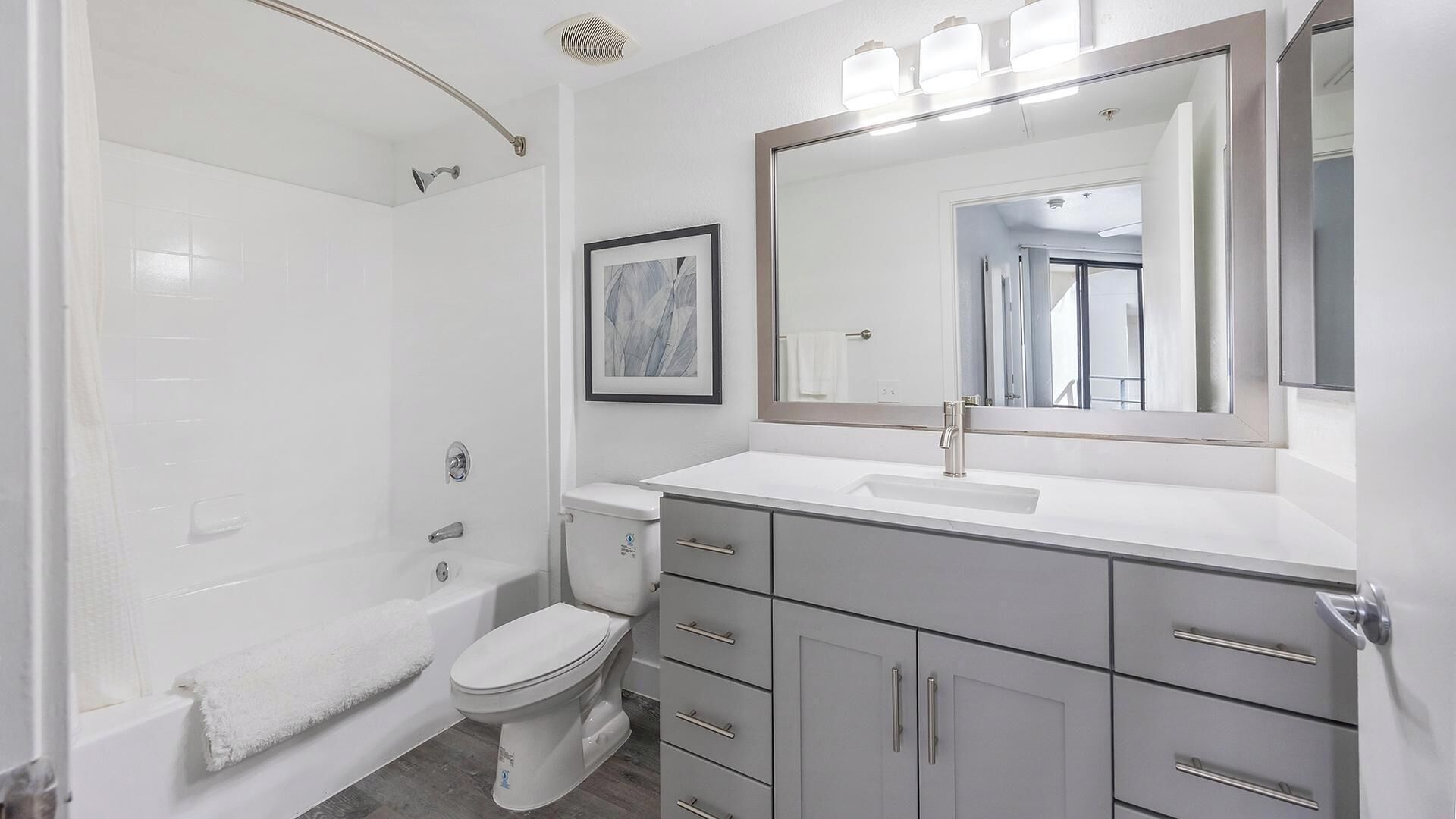 Une salle de bain moderne équipée d’une douche, de toilettes, d’un meuble-lavabo et d’un grand miroir.