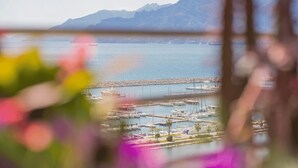 Una marina con barcos amarrados, un muelle que se adentra en el agua y montañas al fondo.